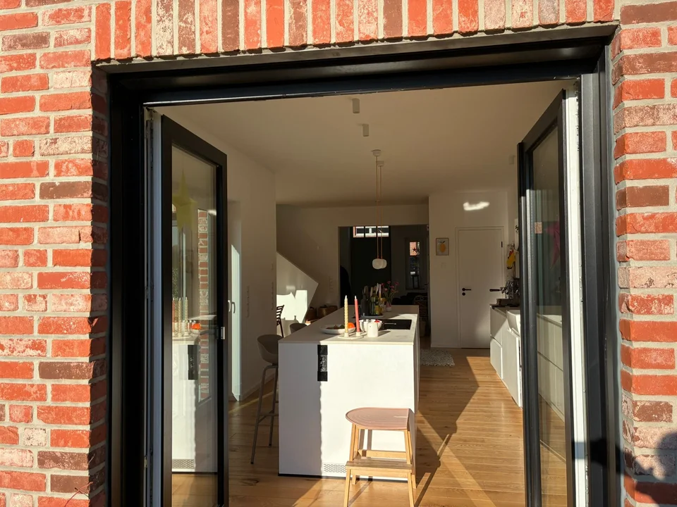 Große Küche mit Kücheninsel im Erker und Blick in den Garten