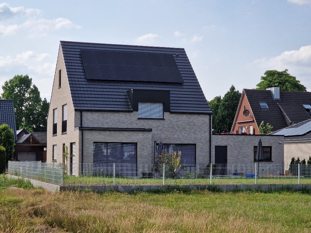 Einfamilienhaus in Messingen – Außenansicht des fertigen Neubaus mit überdachtem Hauseingang in Sichtbetonoptik